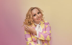 Kaisa Vuorinen katsoo kameraan ja koskettaa kädellään hiuksiaan